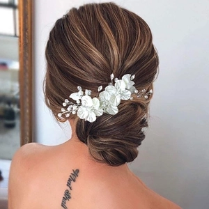 Detail of bridal hair clip with white shell flowers, pearls and crystal beads on a model