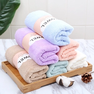 Set of thick coral fleece towels in six pastel colors on a tray for home bathroom use