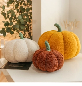 Three multi-colored plush pumpkin pillows in orange, white and brown for home decor