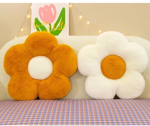 Detailed close-up of plush flower-shaped cushions in orange and white on a soft sofa