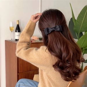 Detail of a black satin bow hair clip styled on hair for an elegant look
