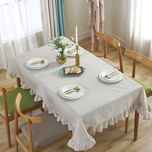 Rectangle beige cotton linen tablecloth with elegant ruffled edges in a warm dining scene
