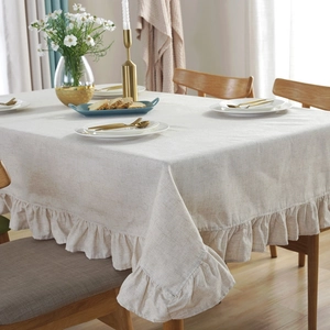 Elegant cream linen tablecloth with ruffled edges on a dining table setup