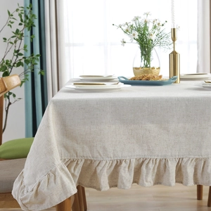 Close-up of beige linen tablecloth featuring vintage ruffled edges in a cozy dining room
