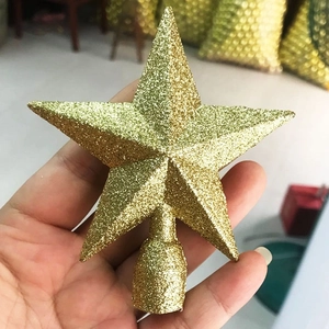 Close-up of a golden glitter star tree topper held by hand for Christmas decor