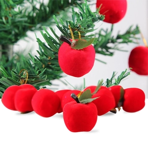 Red flocked Christmas apple ornaments with gold string hanging on green pine branches
