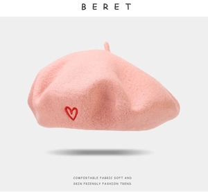 Detailed close-up of pink wool beret featuring a delicate red heart embroidery detail