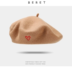 Detail of khaki wool beret showing soft texture and delicate red heart embroidery