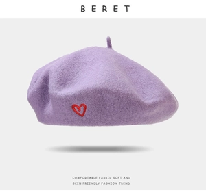 Detail of lavender wool beret featuring a red heart embroidery and soft felt texture