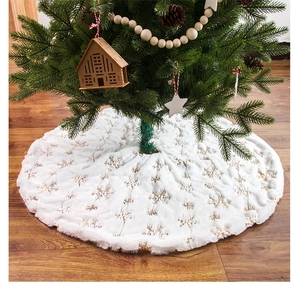 Close-up of white plush Christmas tree skirt with golden snowflake embroidery detail
