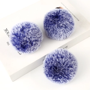 Detail of blue and white faux rabbit fur pom poms on books for bag accessories