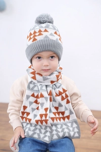 Détail d'un enfant portant un ensemble bonnet et écharpe tricotés avec motif géométrique