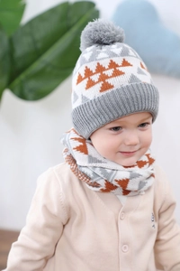 Détail d'un ensemble bonnet et écharpe tricotés pour bébé avec motifs d'arbres et pompon