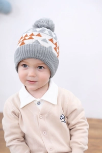 Detail of children's dinosaur jacquard knit hat with thick lining and grey pompom