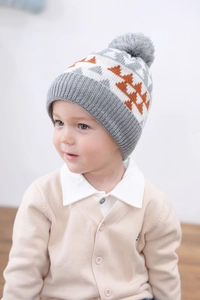 Detailed close-up of a kids knitted dinosaur beanie with pom-pom and soft cotton lining