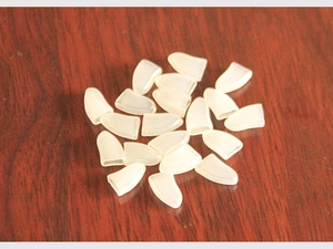 Detail view of 20 soft white silicone pet nail caps for cats on dark wood background