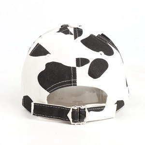 Detail view of cow print baseball cap featuring silver adjustable metal buckle on back
