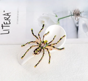 Close-up of a bronze spider brooch with iridescent gemstone and green rhinestones