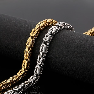 Detail of silver and gold stainless steel Byzantine chains on a black display stand