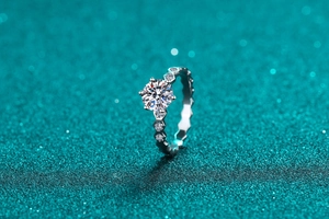 Macro shot of silver S925 moissanite ring with hexagon prongs on a sparkly teal background