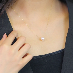 Elegant single freshwater pearl necklace on fine gold chain worn by a female model