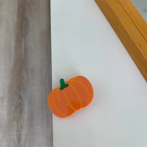 Detail of a small orange pumpkin-shaped enamel brooch with polished finish and metal base