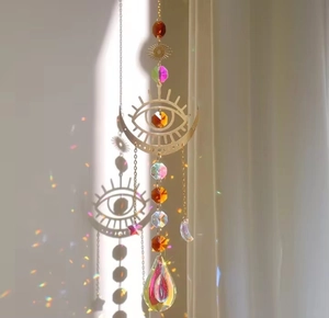 Detailed suncatcher with moon and eye motifs projecting colorful rainbows on wall