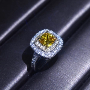 Macro shot of princess cut yellow moissanite ring with double halo and paved band