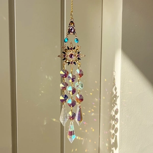 Golden suncatcher with purple gemstones and iridescent crystals reflecting natural light