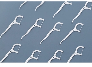 Macro view of multiple high-tensile white plastic dental floss picks neatly arranged