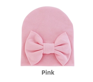 Close-up of soft pink knitted baby hat featuring a large decorative bow for infants