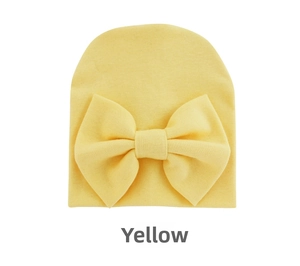 Close-up of yellow knit baby beanie with a large decorative bow on a white background
