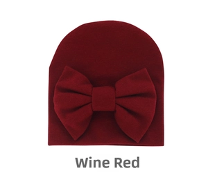 Close-up of wine red newborn hat featuring a soft knitted texture and large bow detail