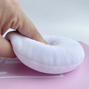 Close-up of soft white velvet powder puff being pressed to show plush texture and elasticity