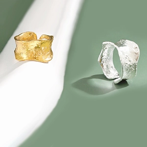 Detail of gold and silver irregular lava rings with hammered texture on fabric background