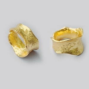 Macro detail of golden irregular lava ring showing textured hammer finish and wide band