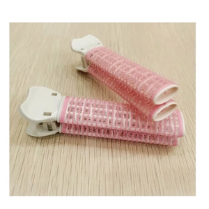 Detailed close-up of pink and white mesh hair root volume clips on a wooden surface