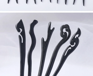 Macro view of five unique black ebony-style wooden hair sticks with intricate carvings