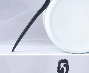 Detailed view of the black wood hair stick featuring a carved hollow swirl cloud design