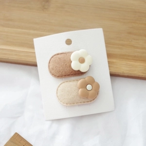 Detailed set of floral BB hair clips on display card with soft beige felt base