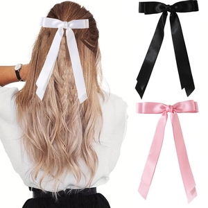 Detailed view of large satin bow hair clips in white black and pink colors