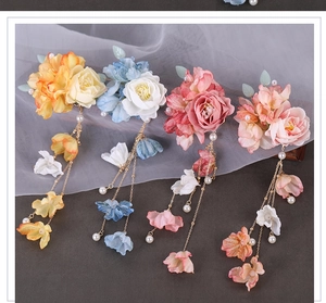 Detail of four colorful Hanfu silk flower hair clips with tassels and pearls on gray fabric