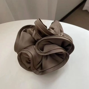 Close-up of a large brown satin silk scrunchie with layered ruffles and soft glossy finish