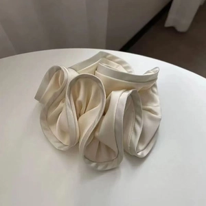 Close-up of cream satin scrunchie with layered ruffles and soft silk texture details