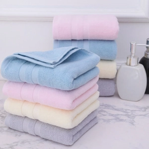 Close-up of thick cotton towels in pastel colors stacked on a marble bathroom counter