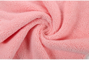 Close-up of soft pink coral fleece fabric showing the thick plush spiral texture