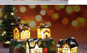 Detail of four glowing resin Christmas village houses with warm LED lighting effects