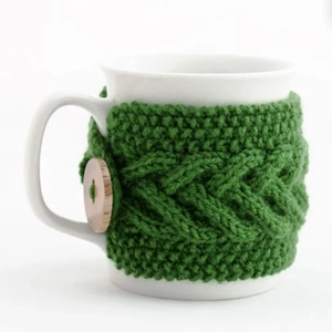 Handmade green crochet mug cozy with cable knit pattern and wooden button detail