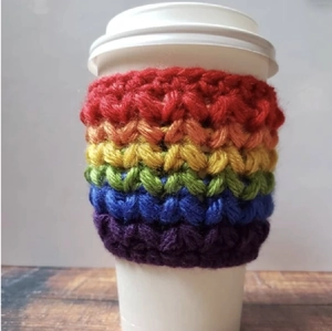 Close-up of handmade rainbow crochet mug sleeve on a cup for insulation and decor