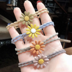 Detailed view of four colorful daisy flower elastic hair ties worn on a wrist